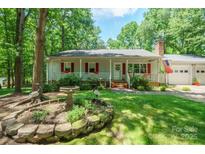 Charming home features a landscaped front yard with stone accents and a welcoming porch at 116 April Ln, Dallas, NC 28034