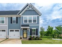 Charming townhome featuring a well-manicured lawn, attached garage, and inviting blue siding at 154 Stella Ln # A, Troutman, NC 28166