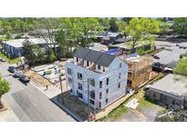 New construction shows a modern, multi-story home with a dark roof and large windows and a wood frame next door at 411 Devender Ne Ln # 5, Charlotte, NC 28217