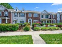 Charming townhome with brick and siding exterior, manicured landscaping, and a picket fence under a clear, blue sky at 7007 Creft Cir, Indian Trail, NC 28079