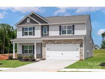 Two-story home with stone accents, a two-car garage, light gray siding, and a manicured lawn at 7311 Jerimoth Dr, Charlotte, NC 28215