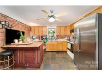 Spacious kitchen featuring wood cabinets, stainless steel refrigerator, ceiling fan, and a center wooden island at 11201 Johnson Davis Rd, Huntersville, NC 28078