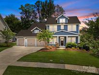 Charming two-story home with blue siding, landscaped front yard, and a three-car garage on a beautiful lot at 11329 Fullerton Place Nw Dr, Huntersville, NC 28078
