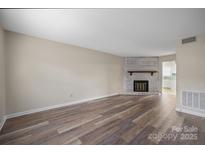 Bright living room featuring a brick fireplace and hardwood floors; open floor plan at 1330 5Th Ne St, Hickory, NC 28601