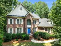 Charming two-story brick home with a blue front door, lush landscaping, and a classic architectural design at 15400 Groveland St, Huntersville, NC 28078