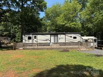 Charming RV with a spacious wooden deck and a surrounding fence, nestled in a serene wooded area at 155 Indian Harbor Trl # E243, Mount Gilead, NC 27306
