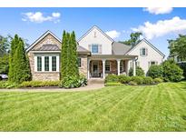 Beautiful home with a stone and stucco exterior, manicured lawn, and inviting front porch at 2501 Christenbury Hall Nw Ct, Concord, NC 28027