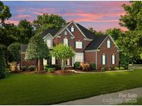 Beautiful two-story brick home with a well-manicured lawn and colorful sunset backdrop at 2504 Fallbrook Pl, Concord, NC 28027