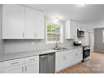 Bright kitchen featuring granite countertops, stainless steel appliances, and white cabinetry at 346 Fieldstone Cir, Statesville, NC 28677