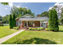 Charming brick home featuring a welcoming front porch, manicured lawn, and mature landscaping at 628 Stamie Dr, Chester, SC 29706