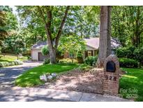 Charming single-story brick home featuring mature trees, lush landscaping, and a welcoming front lawn at 928 Tally Ho Ct, Charlotte, NC 28212
