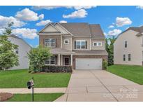 Beautiful two-story home with a brick and tan exterior, well-manicured lawn, and an attached two-car garage at 1349 Bridgeford Nw Dr, Huntersville, NC 28078