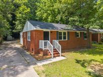 Charming single-story brick home featuring a well-manicured lawn and a welcoming front porch with white railings at 1709 Masonic Dr, Charlotte, NC 28205