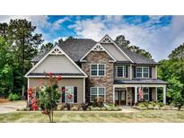 Charming two-story home with a stone facade, manicured lawn, and inviting front porch at 3963 Harmattan Dr, Denver, NC 28037