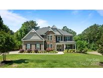Charming two-story home with a stone and brown exterior, complemented by a lush green lawn and mature trees at 3963 Harmattan Dr, Denver, NC 28037