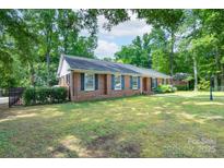 Charming brick home featuring a manicured lawn and black shutters amidst mature trees, offering classic curb appeal at 5720 Amity Pl, Charlotte, NC 28212