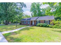 Charming one-story brick home with a well-manicured lawn, blue hydrangeas, and a inviting walkway to the front door at 5720 Amity Pl, Charlotte, NC 28212