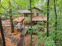 Secluded two-story house featuring mature landscaping, a large deck, and wooden exterior at 676 Cottingham Ne Pl, Concord, NC 28025