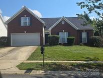 Charming brick home featuring a well-maintained lawn and a two-car garage at 13409 Planters Row Dr, Charlotte, NC 28278