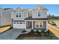 Two-story home featuring a grey exterior, two-car garage, covered porch, and well-maintained landscaping at 14113 New Crest Ln # 153, Huntersville, NC 28078