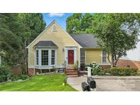 Charming yellow home featuring a red door, bay window, and beautifully landscaped front yard at 2308 Blair House Ct, Charlotte, NC 28270