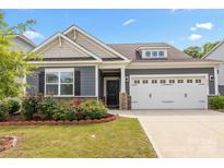 Charming home featuring a two-car garage, stone accents, manicured lawn, and delightful red roses at 4427 Poplin Grove Dr, Indian Trail, NC 28079