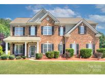 Charming brick two-story home featuring a well-manicured lawn, black shutters, and a welcoming front porch at 604 Palmerston Ln, Waxhaw, NC 28173