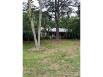Charming single-story brick home with a metal roof, surrounded by mature trees and a lush lawn at 7501 Glencannon Dr, Charlotte, NC 28227