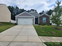 Charming single-story home features a two-car garage, stone accents, and a well-manicured front yard at 10410 Bradstreet Commons Way, Charlotte, NC 28215