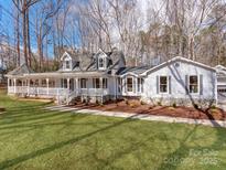 Charming two-story home with a covered porch, lush lawn, and mature trees, offering a serene and inviting curb appeal at 107 Rutledge Rd, Mount Holly, NC 28120