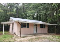 Cozy single-story home with a metal roof, covered porch, and green shutters surrounded by lush greenery at 11550 Us Hwy 52 N Hwy, Ansonville, NC 28170