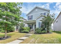 Charming two-story home with blue shutters and a well-manicured front lawn and lush greenery at 11733 Mesquite Rd, Huntersville, NC 28078