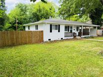 Charming single story home featuring a covered porch, dark shutters and wood fence at 1211 Campus St, Charlotte, NC 28216