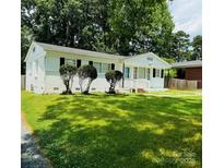 Charming white home with black shutters and well-maintained lawn, complemented by lush trees in the background at 1211 Campus St, Charlotte, NC 28216