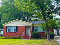 Charming red brick home featuring a well-maintained lawn and mature shade trees at 208 S Thompson St, Monroe, NC 28112