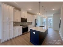 Modern kitchen boasts white cabinets, stainless appliances, and a large island with quartz countertops at 3618 S Tryon St # 19, Charlotte, NC 28217
