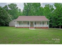 Charming home featuring a covered porch with white railings, a brick foundation, and lush green lawn at 441 Vermilion Dr, York, SC 29745