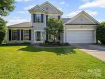 Charming two-story home with light grey siding, black shutters, well-maintained lawn and attached two-car garage at 5921 Firethorne Ln, Concord, NC 28025