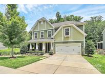 Charming two-story home featuring a manicured lawn, a two-car garage, and classic architectural details at 7011 Hyde Park Dr, Indian Trail, NC 28079
