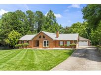 Charming one-story brick home features a well-manicured lawn and an inviting entrance with mature trees surrounding the property at 8007 Caldwell Rd, Harrisburg, NC 28075