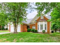 Traditional brick home with manicured lawn, mature trees, and attached two-car garage at 13402 Mccoy Rd, Huntersville, NC 28078