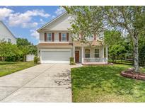 Charming two-story home featuring a well-manicured front yard, a front porch, and an attached two-car garage at 13622 Stringfellow Ln, Charlotte, NC 28278