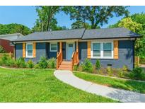 Charming renovated home with blue painted brick, light blue door, new gray roof, wood porch and accent shutters at 2116 Eastway Dr, Charlotte, NC 28205