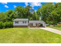 Charming single-Gathering home featuring a lush green lawn, a convenient carport, and beautiful brick accents at 416 Donna Ave, Gastonia, NC 28052
