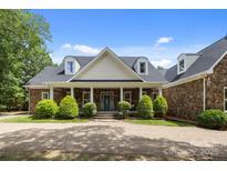 Beautiful stone house featuring a manicured lawn, dormer windows, and a charming front porch with stone columns at 9261 Marvin School Rd, Marvin, NC 28173