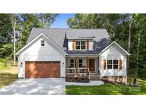 Charming two-story home with white siding, dark roof, inviting front porch, and a well-maintained, attached brown garage at 1004 E Sandy Ridge Rd, Monroe, NC 28112