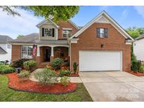 Charming brick home with a two-car garage, landscaped yard, and a welcoming covered front porch at 10919 Valley Spring Dr, Charlotte, NC 28277