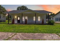 Charming white home with a welcoming porch and well-manicured lawn, ideal for Gathering living at 113 Woodside Ave, Gastonia, NC 28054
