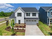 Charming two-story home showcasing manicured landscaping, a welcoming porch, and an attached two-car garage at 12009 Grinstead Ln # 303, Charlotte, NC 28278