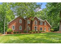 Charming red brick home with lush green lawn and mature trees offering curb appeal and natural beauty at 1310 Weddington Hills Dr, Matthews, NC 28104